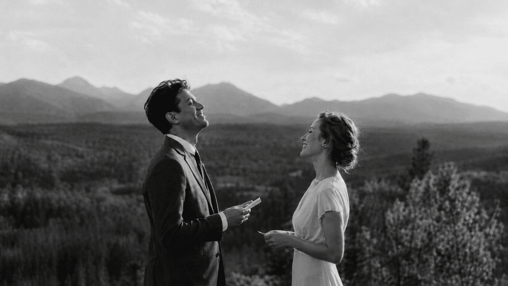 Wedding couple laughing during vows in front of mountain scenery